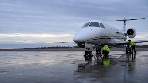 Business jet on a regional airport ramp at dawn with ground crew placing chocks