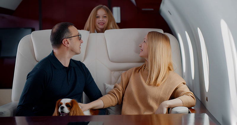 Happy family with cocker spaniel dog flying together on private jet