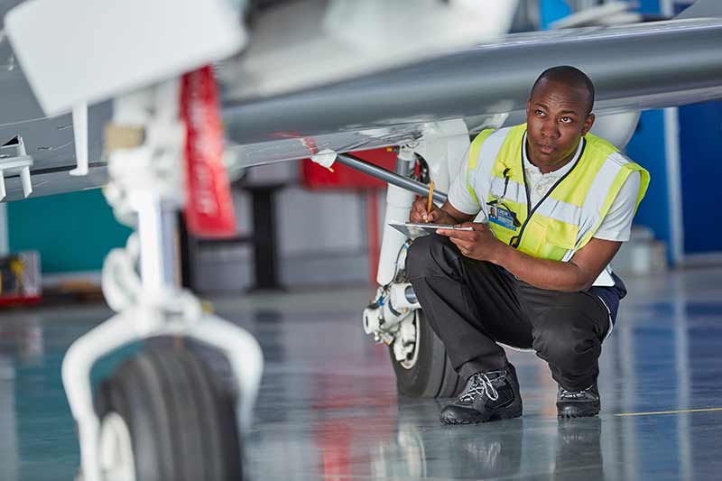 Aviation technician inspecting the landing gear of a private jet during a safety check.
