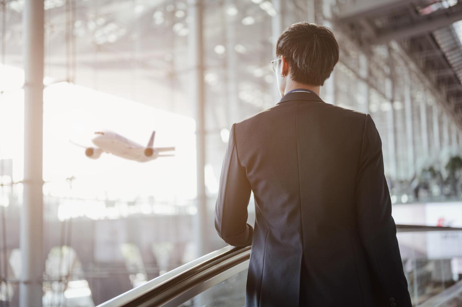 man looking at jet through airport window